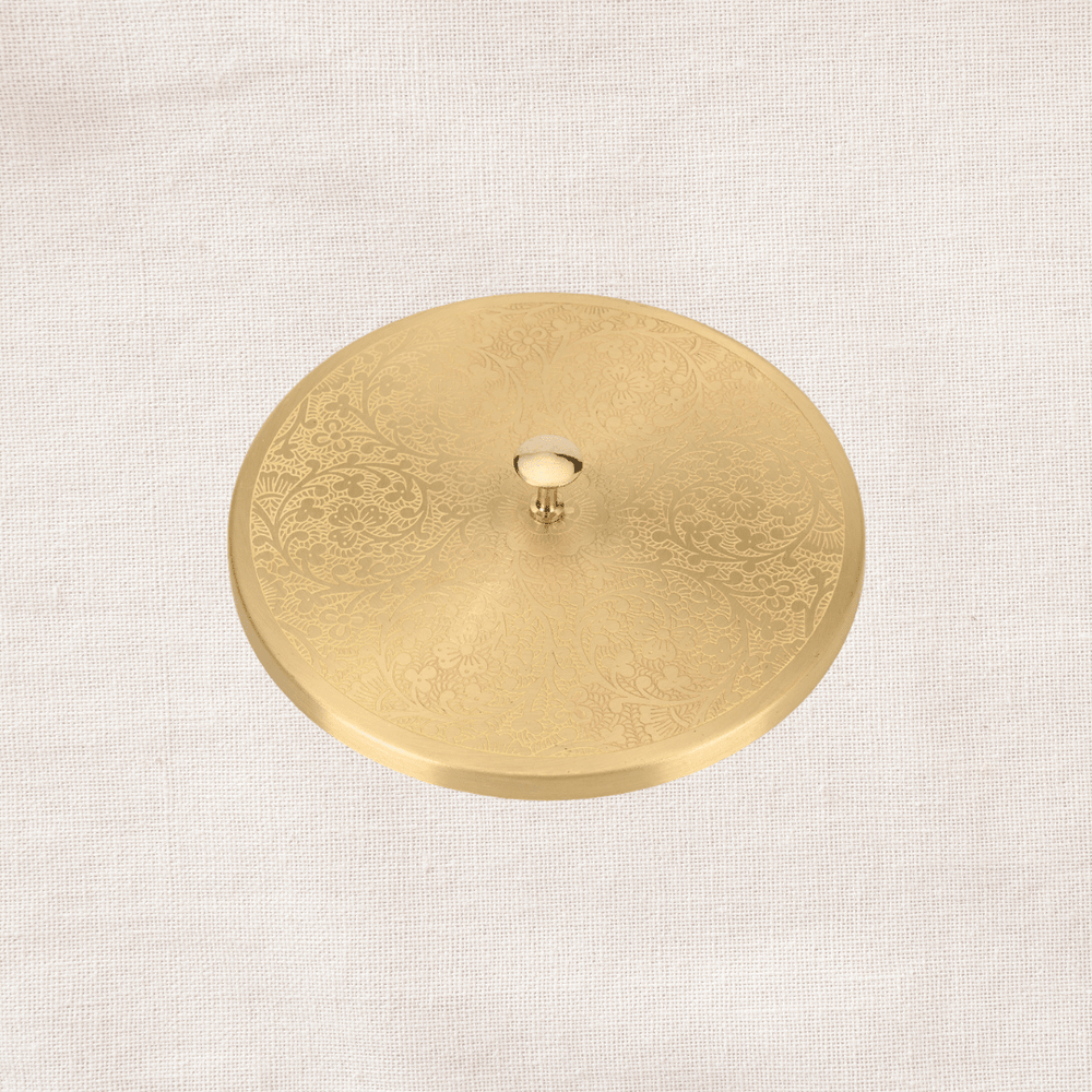 Angled view of engraved brass lid of masala dabba