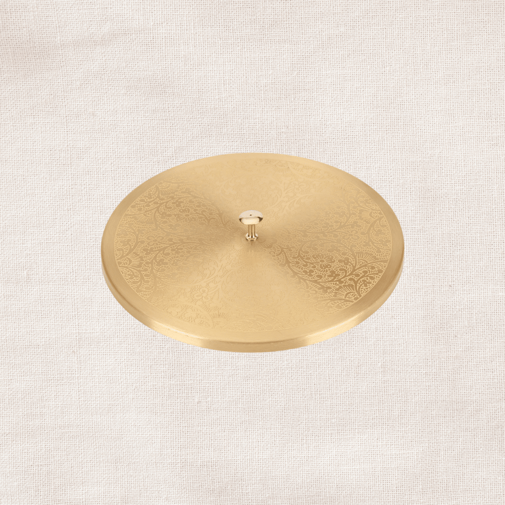 Angled view of engraved brass lid of masala dabba